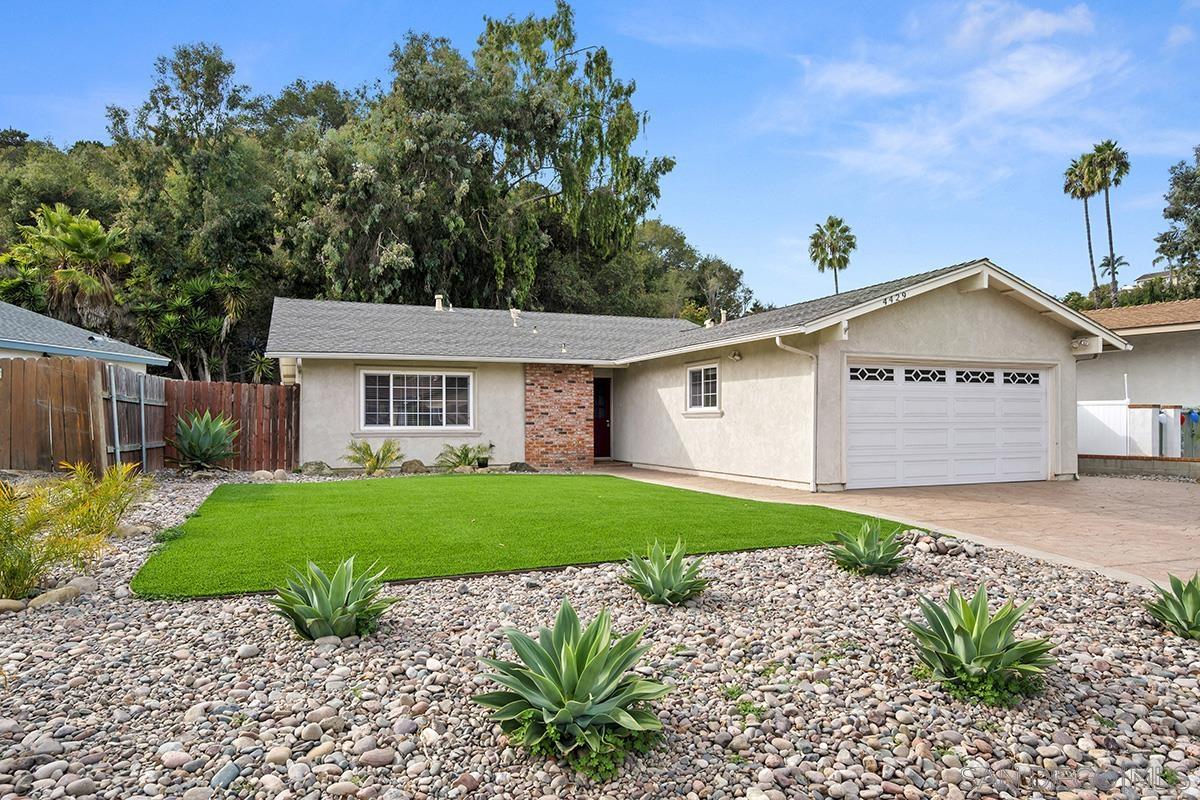 a view of a yard in front of a house with a large tree