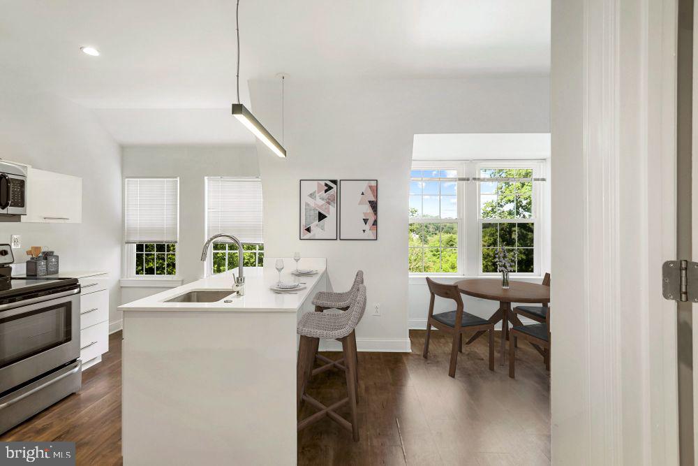 a room with stainless steel appliances kitchen island granite countertop furniture and a wooden floor