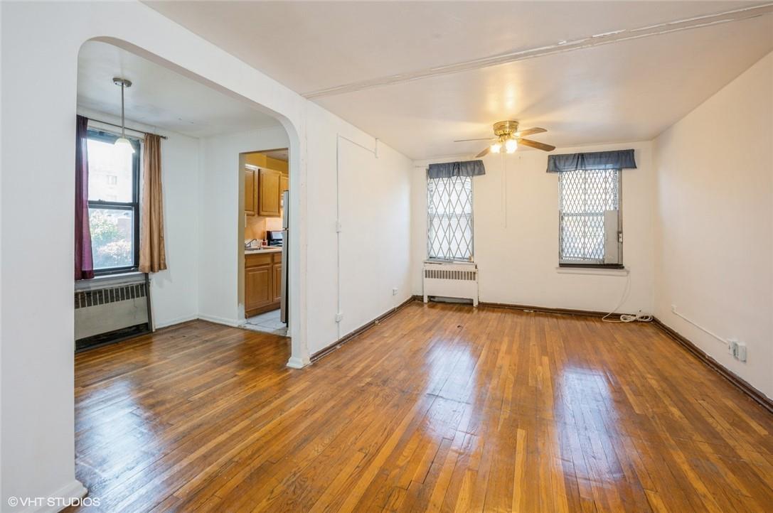 Unfurnished living room with ceiling fan, radiator heating unit, and dark hardwood / wood-style floors