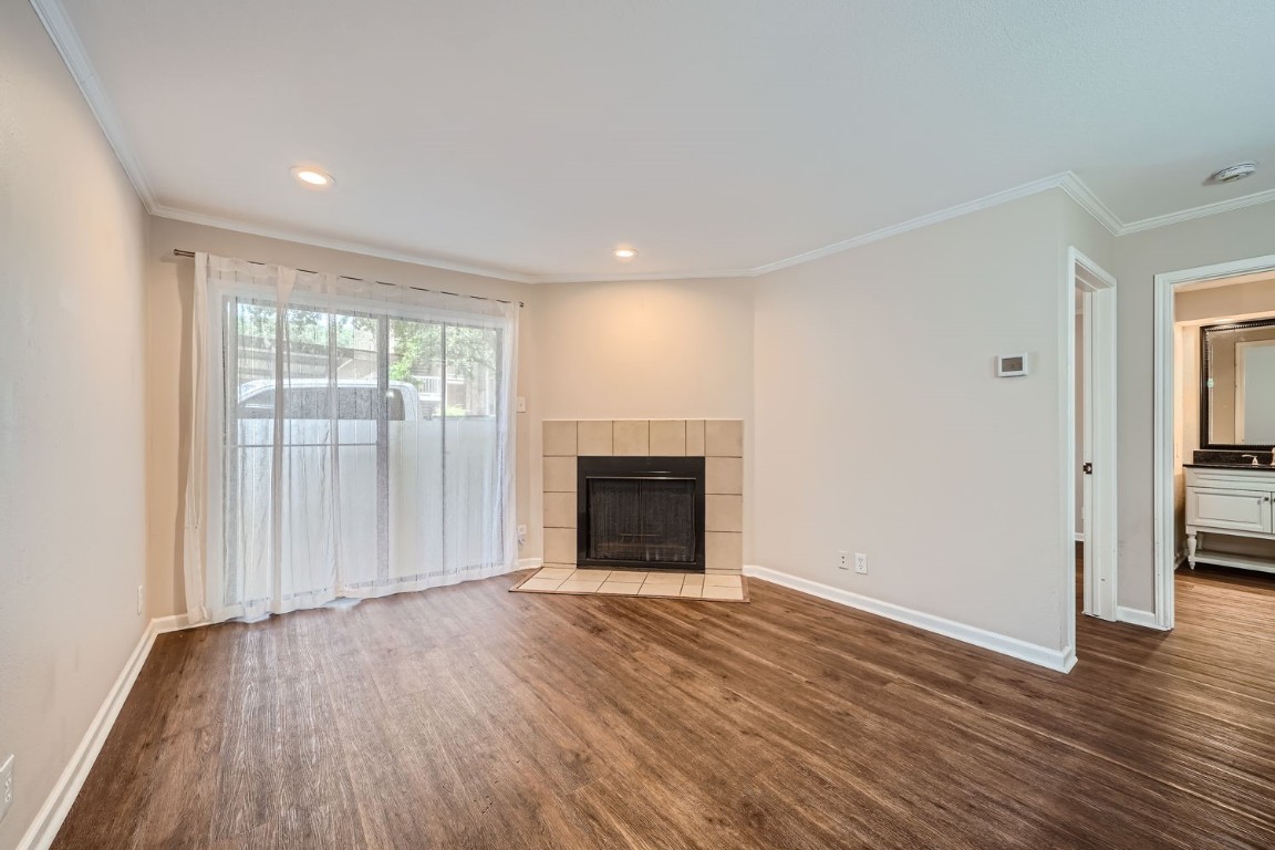 an empty room with wooden floor fireplace and windows