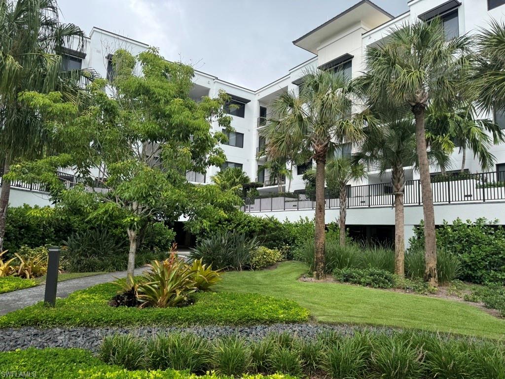 a view of a garden with a fountain plants and large tree