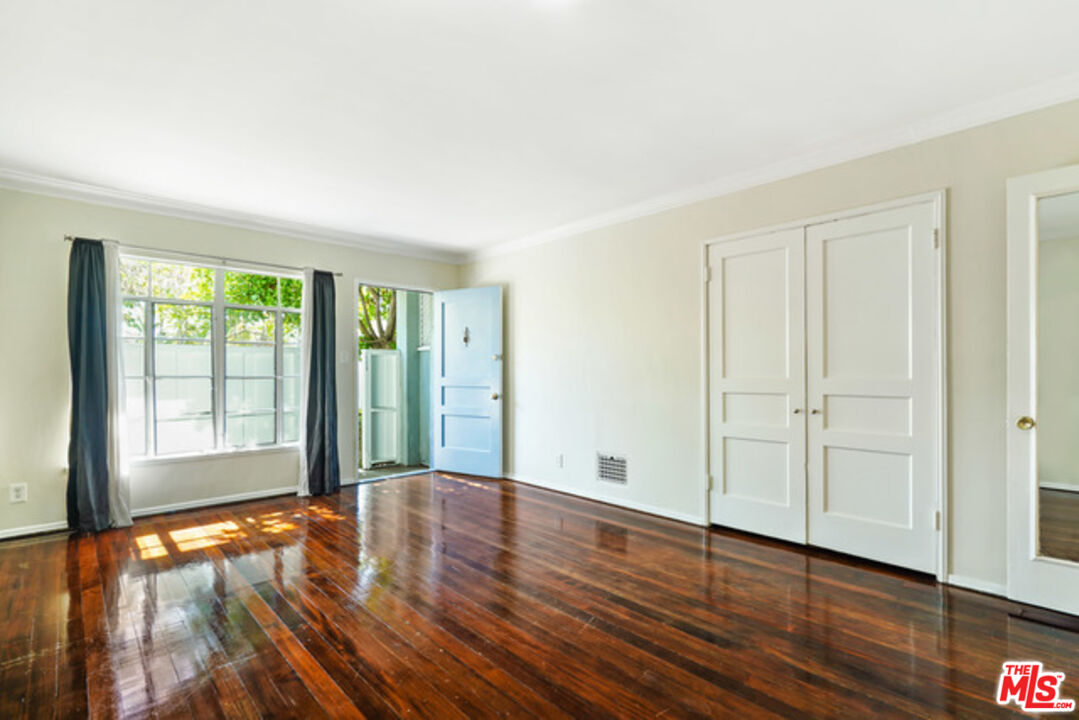 an empty room with wooden floor and windows