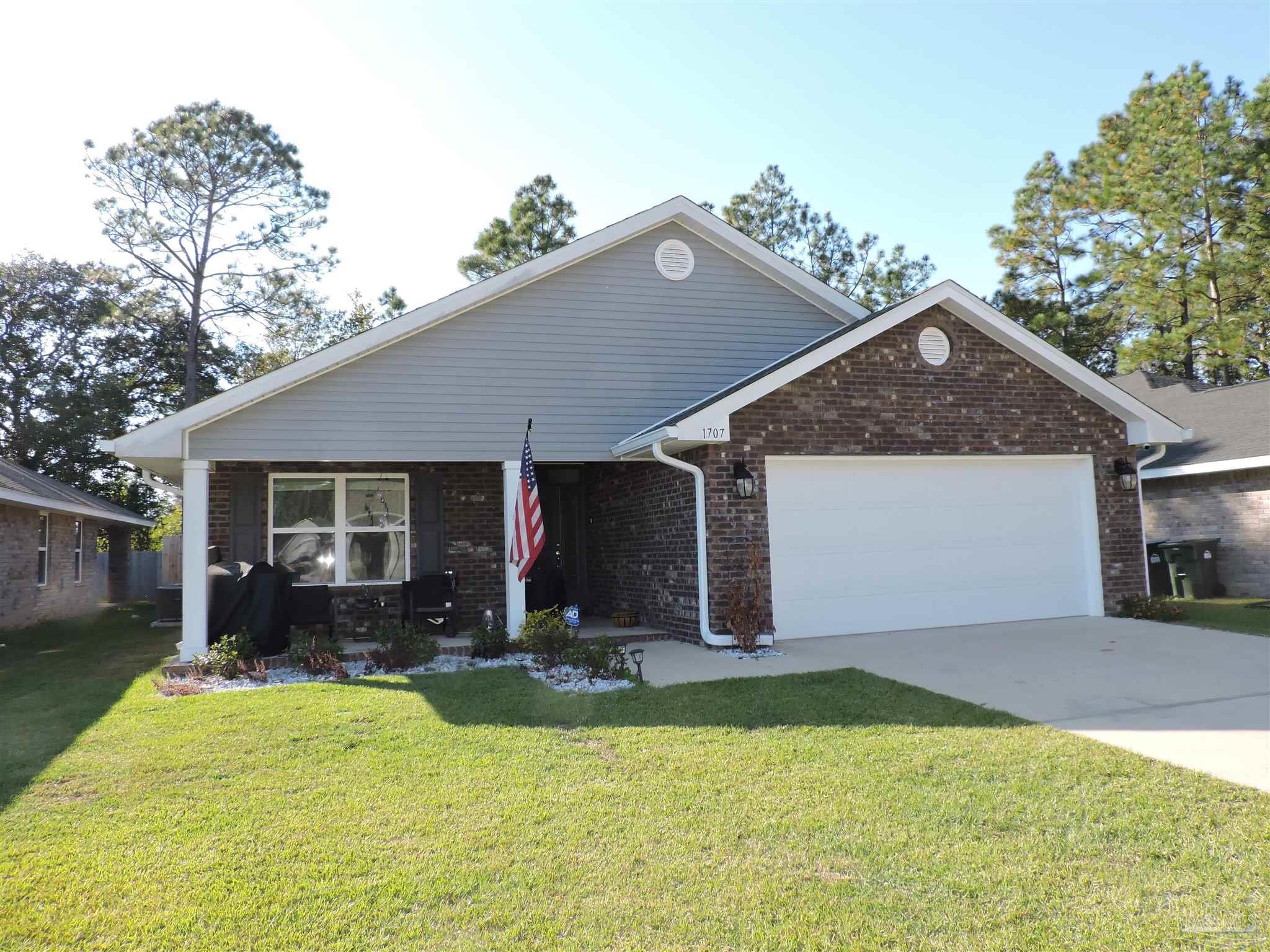 a front view of house with yard and trees in the background