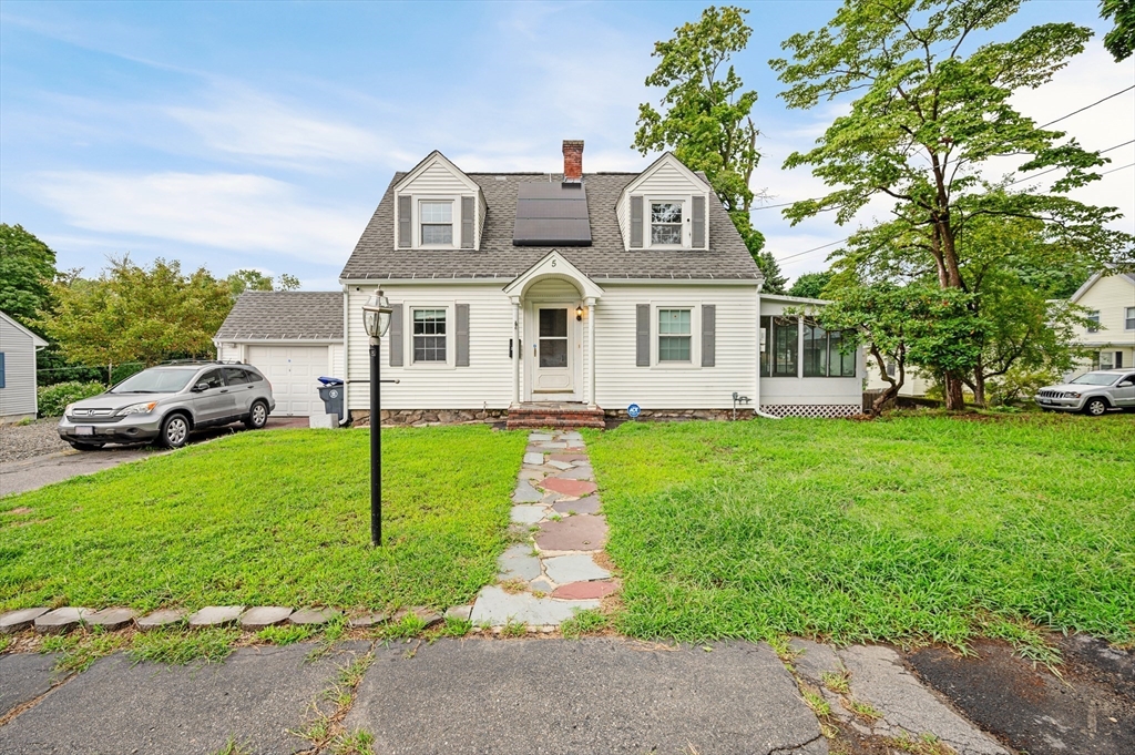 a front view of a house with a garden and trees