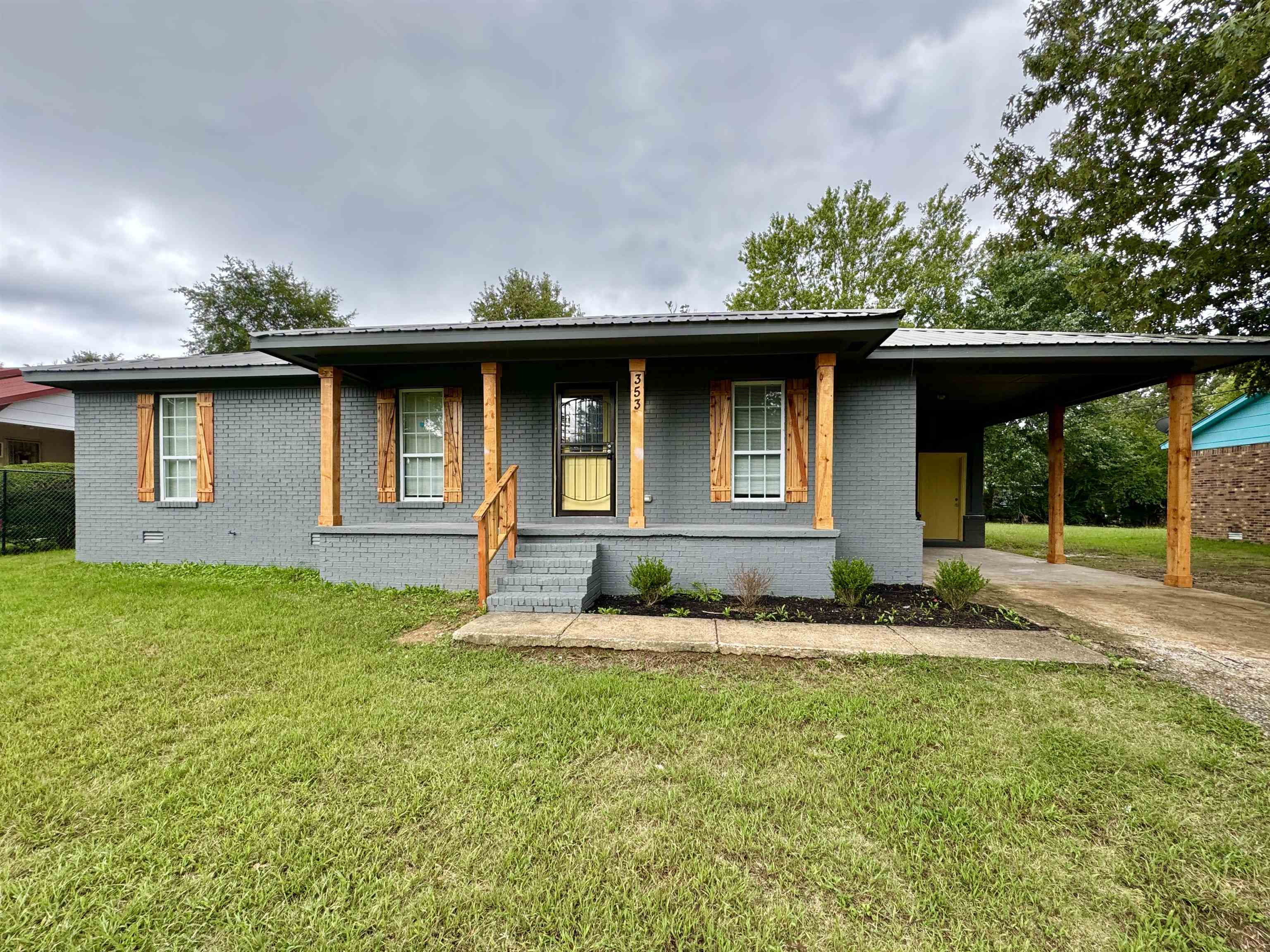 View of front of property featuring a front yard and a carport