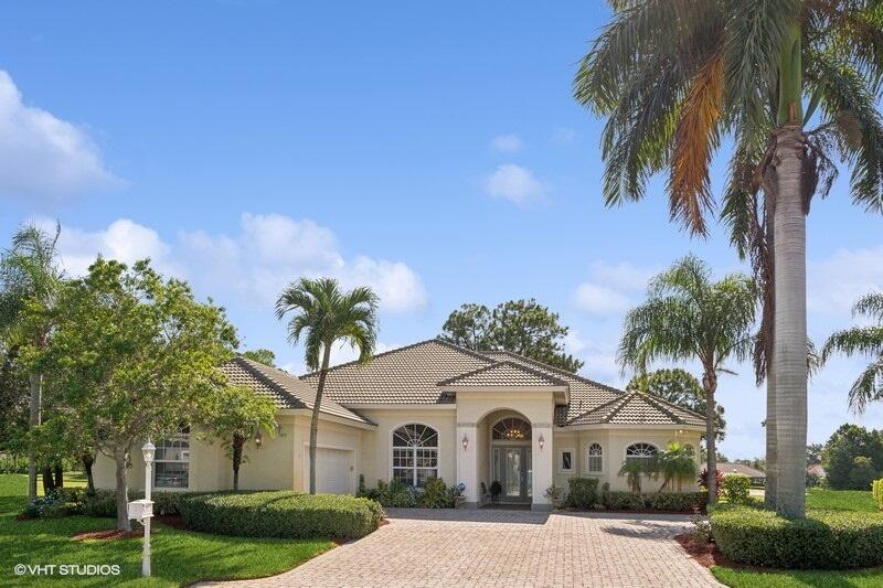 a view of a white house with a yard and palm trees