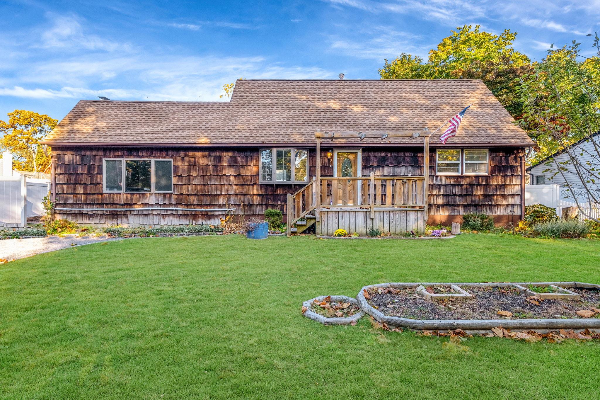 Back of house with a deck and a lawn