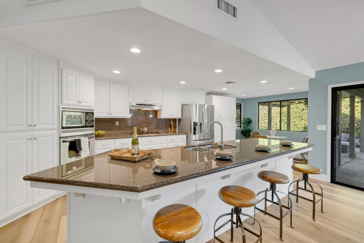 a kitchen with stainless steel appliances granite countertop a sink and a refrigerator