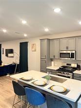 a kitchen with stainless steel appliances granite countertop a stove a sink a microwave a dining table and chairs