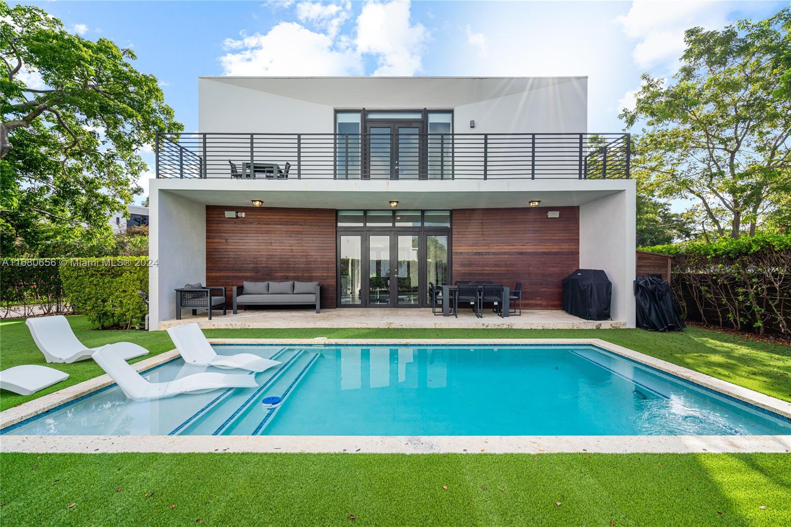 a view of swimming pool with lawn chairs and plants