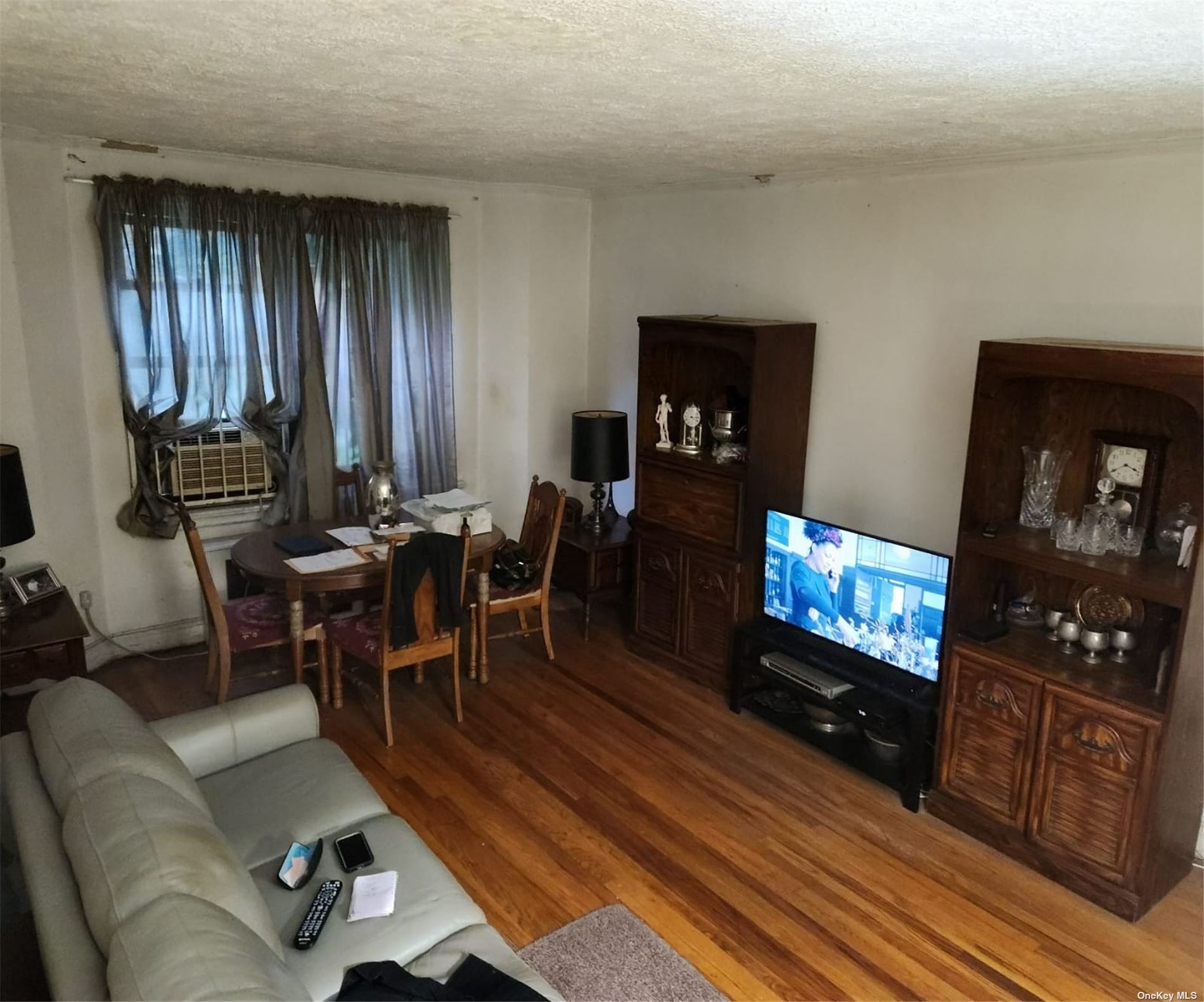 a living room with furniture a dining table a lamp and a flat screen tv