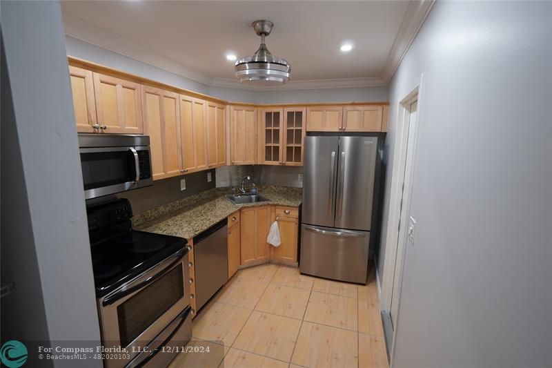 a kitchen with granite countertop a refrigerator and a stove top oven