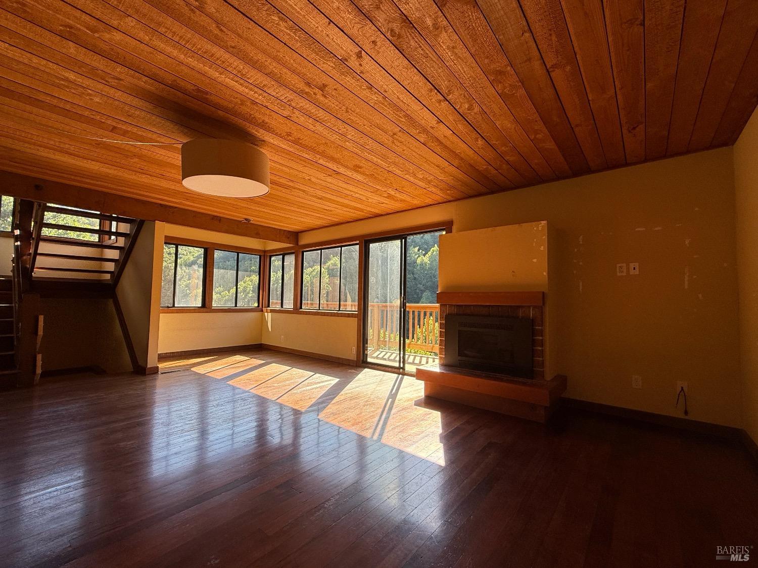 a view of an empty room with wooden floor and a floor to ceiling window