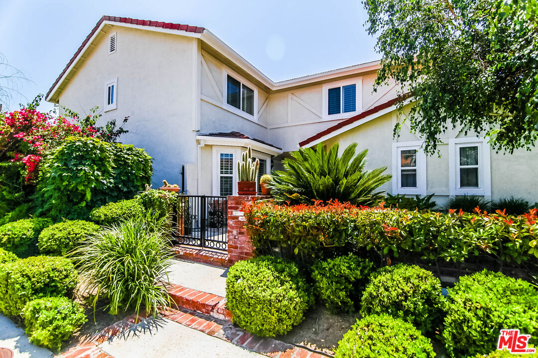 a front view of house and yard with beautiful flowers