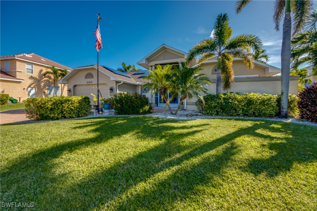 a front view of a house with a yard and palm trees