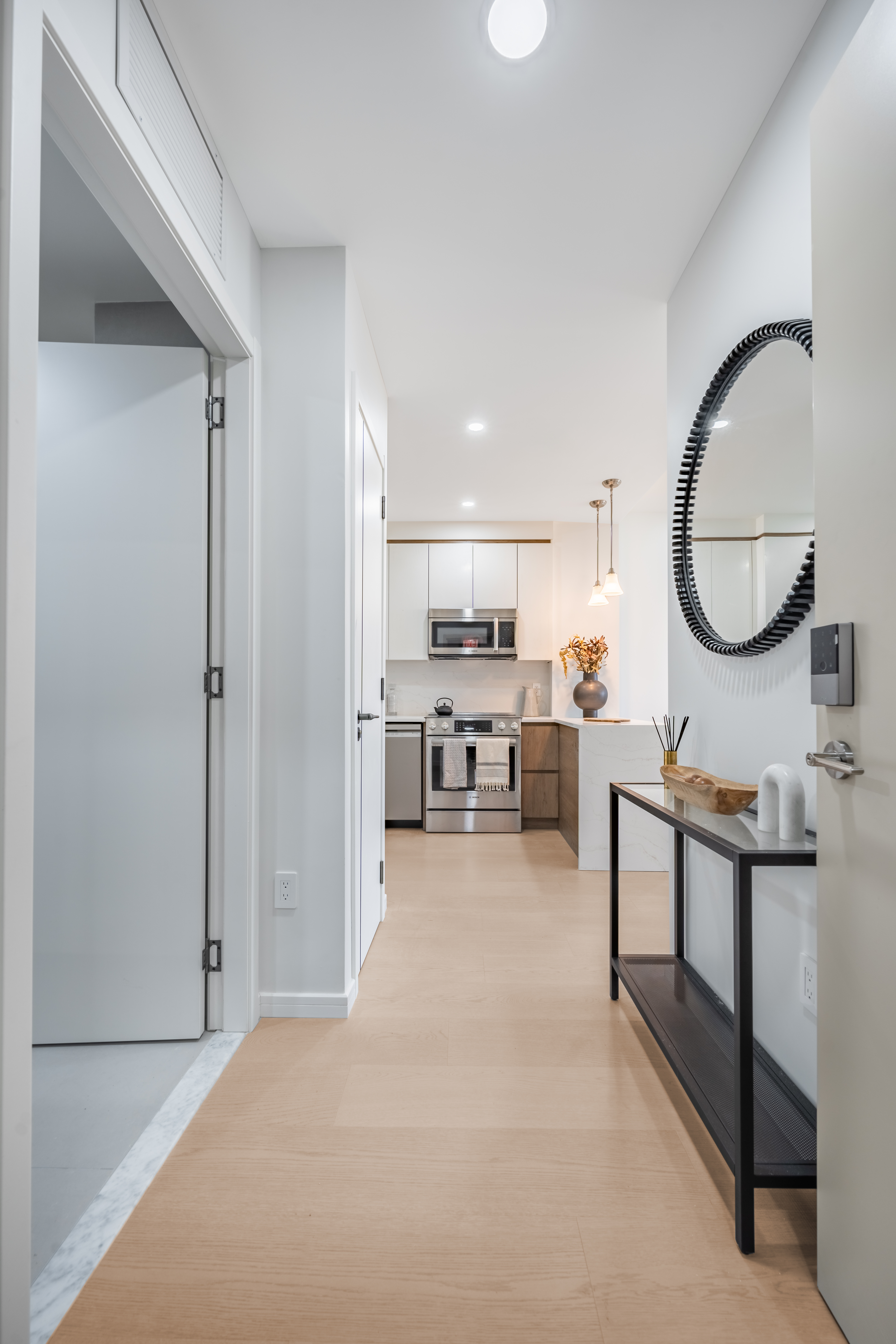 a living room with stainless steel appliances furniture a rug and a kitchen view