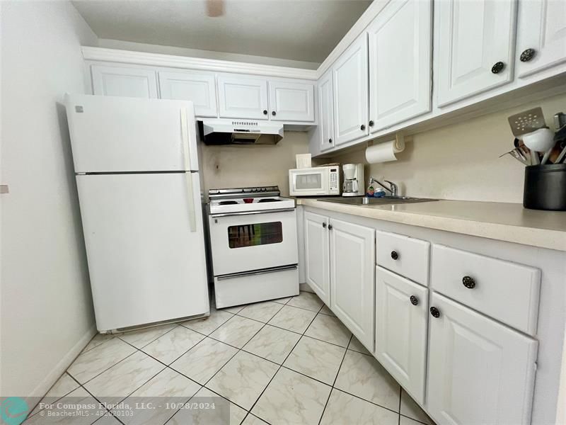 a kitchen with white cabinets and white appliances