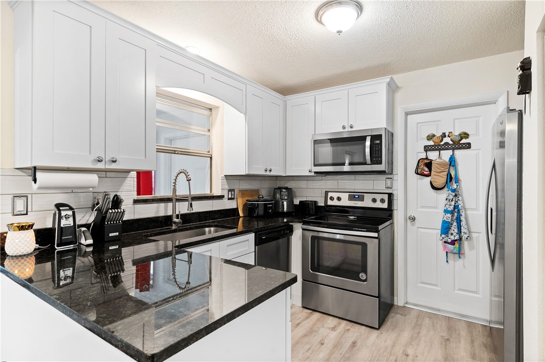 a kitchen with stainless steel appliances granite countertop a stove a sink and a microwave