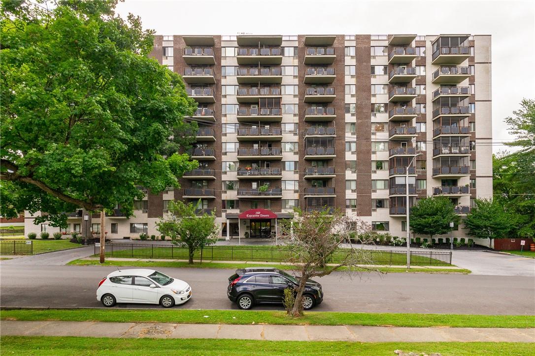 a front view of a building with cars parked