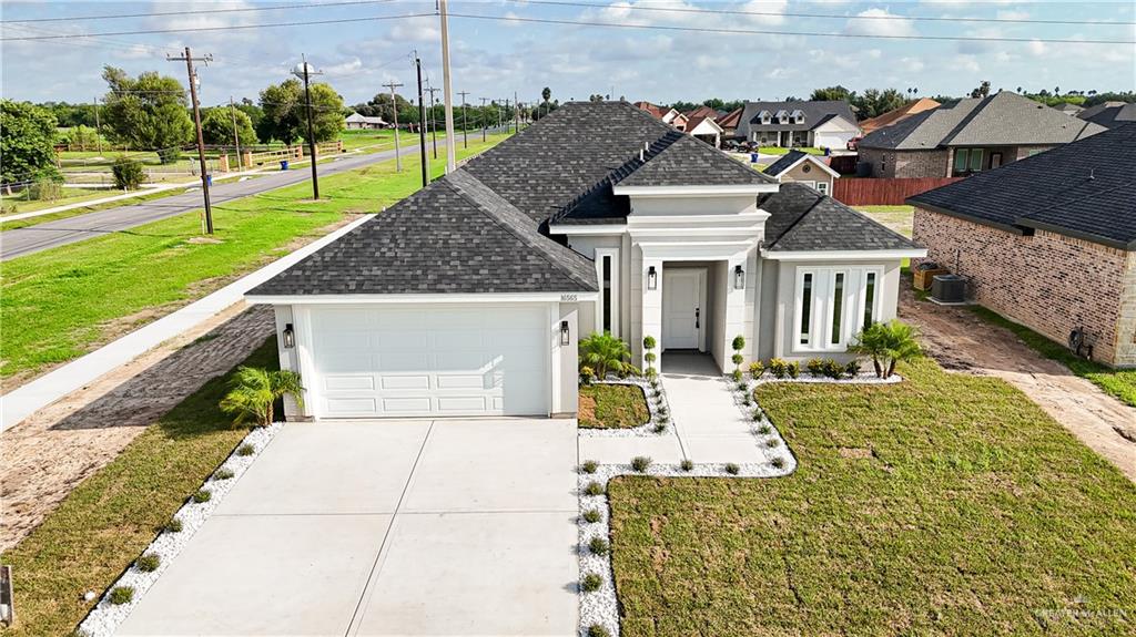 View of front facade featuring cooling unit, a front lawn, and a garage