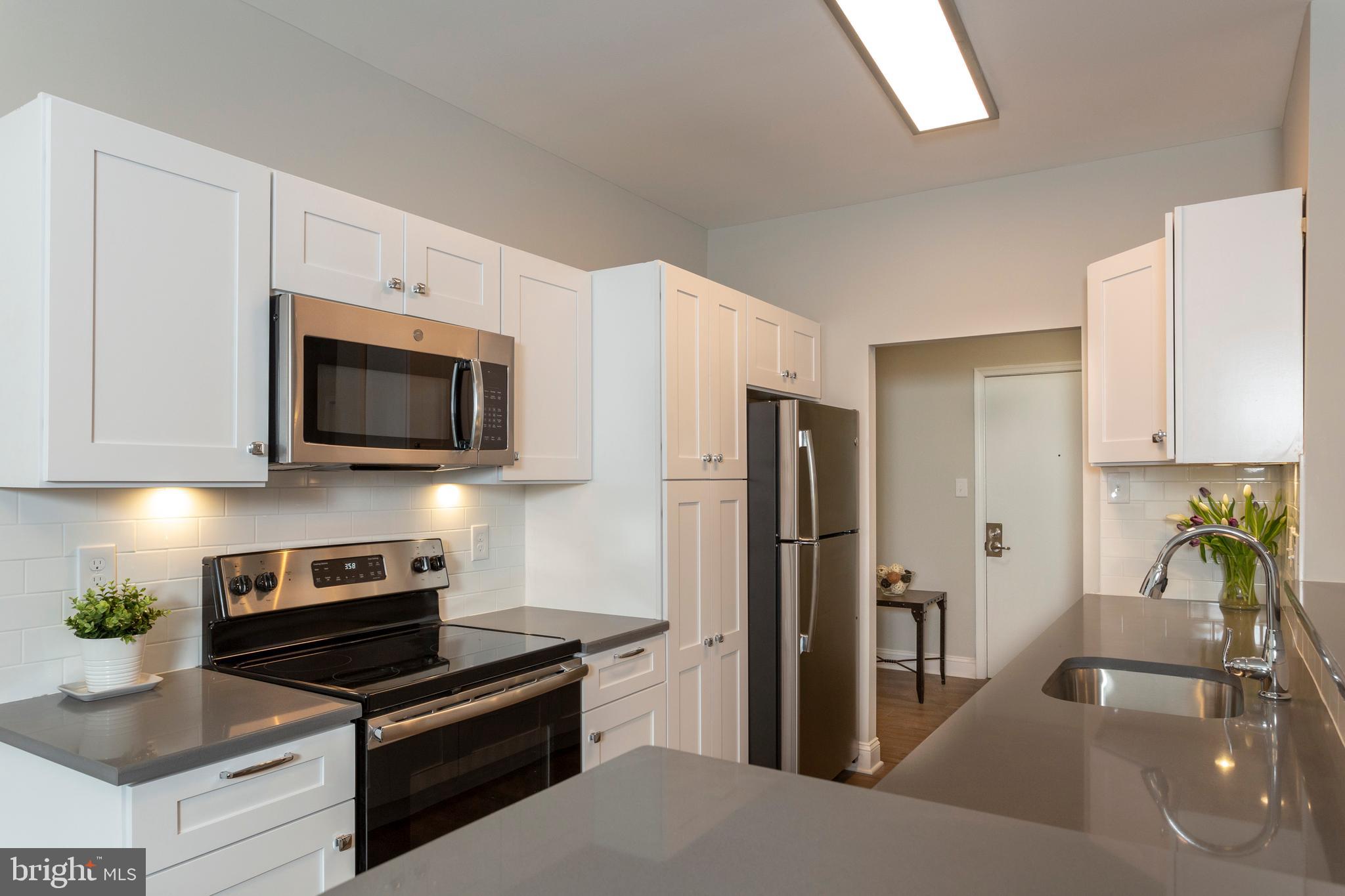 a kitchen with granite countertop a refrigerator a stove and a sink