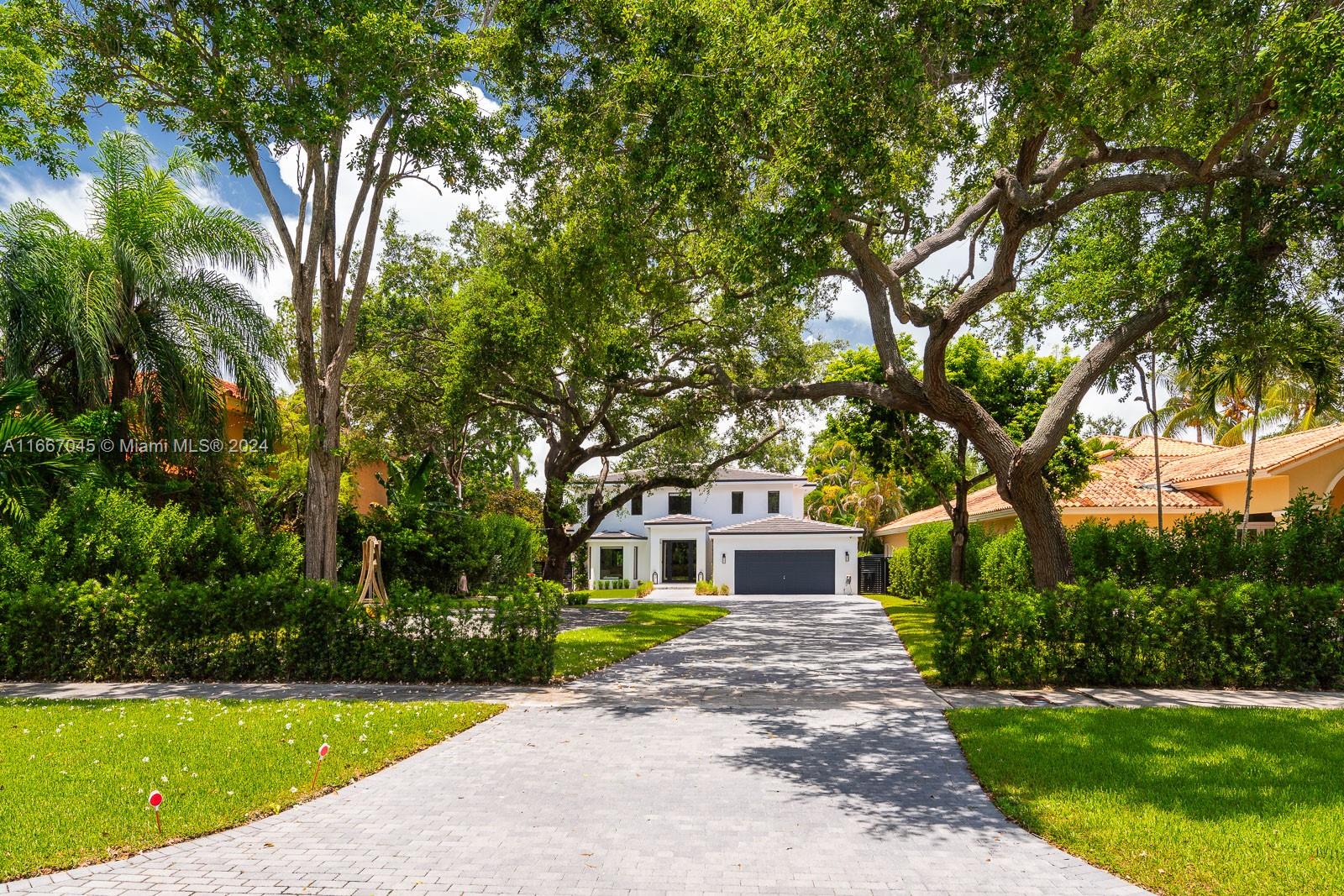 a front view of a house with a garden and trees