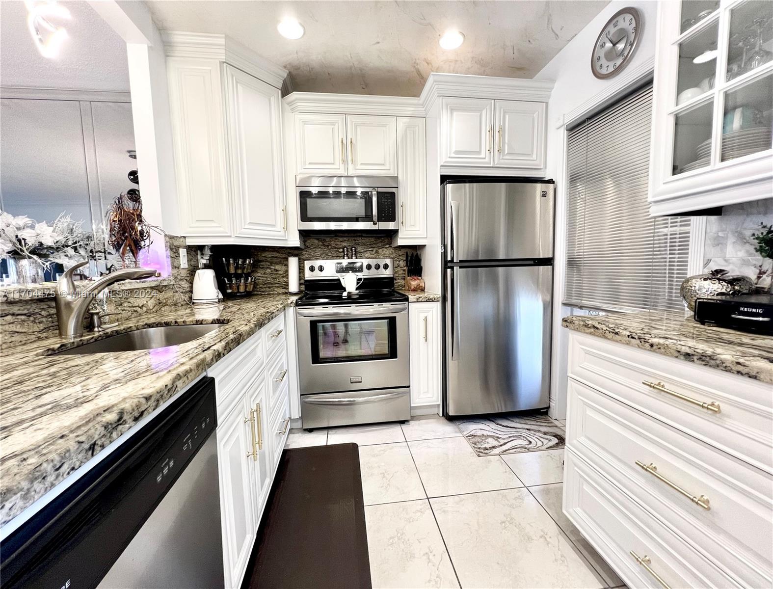 a kitchen with stainless steel appliances granite countertop a refrigerator a stove and a sink with wooden floors