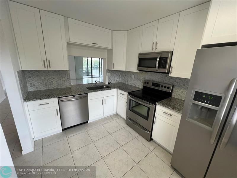 a kitchen with a sink white cabinets and stainless steel appliances