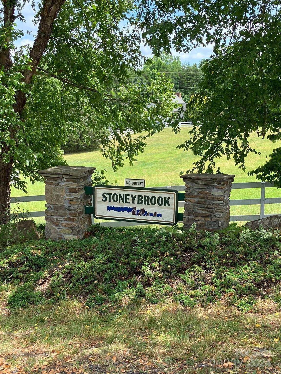 a sign of golf club on a wall under a tree