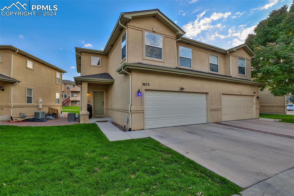 View of front of property with a front yard, a garage, and central AC unit