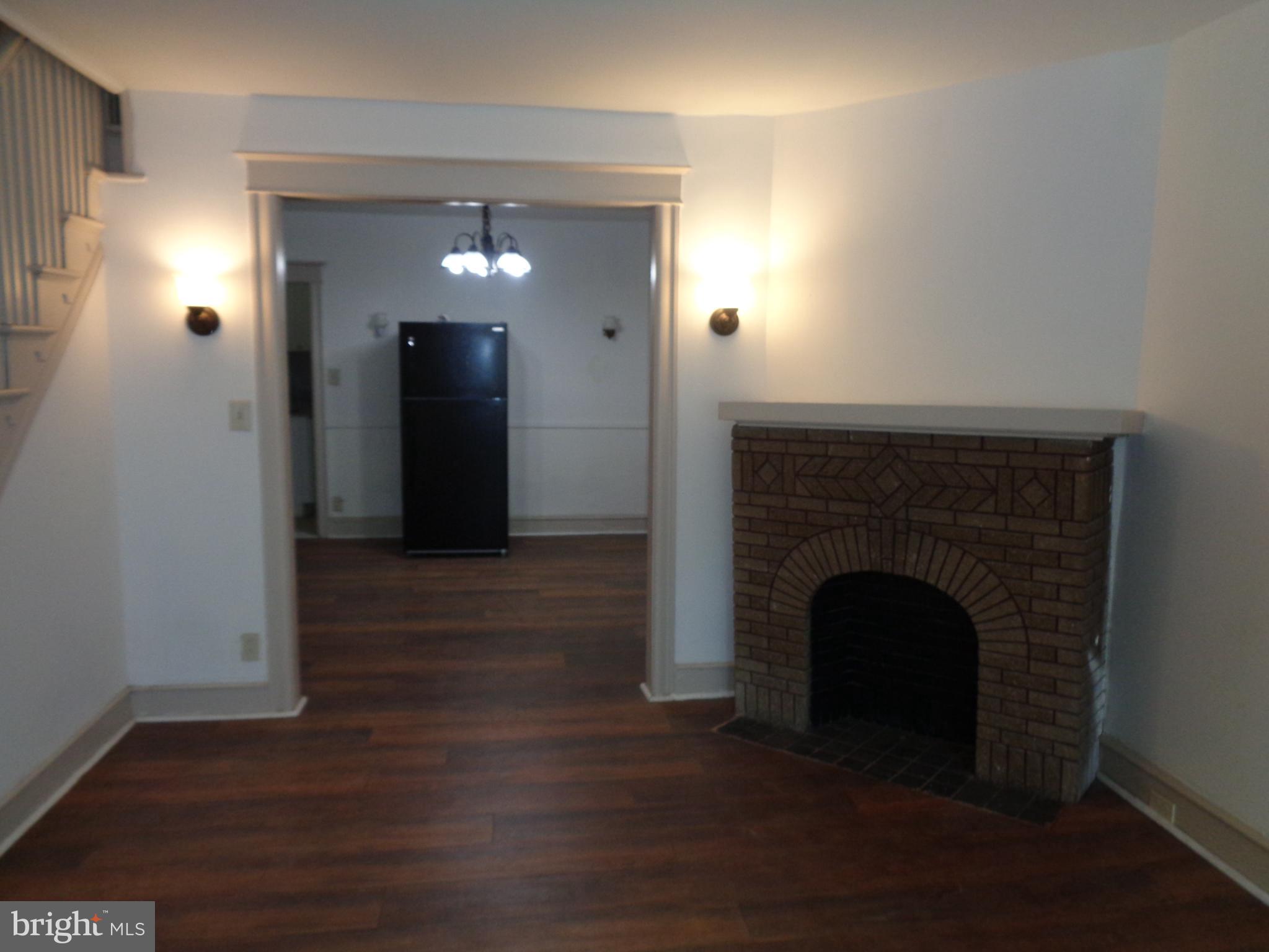 a view of an empty room with wooden floor and a fireplace