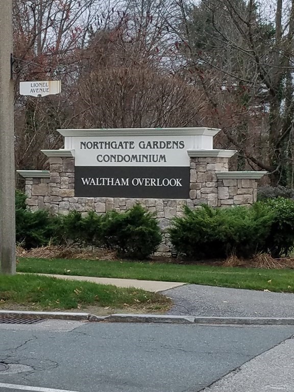 a view of a park that has a sign board large trees