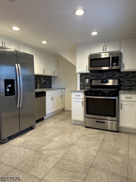 a kitchen with stainless steel appliances granite countertop a stove a refrigerator and a microwave