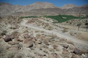 a view of a dry field with mountains in the background