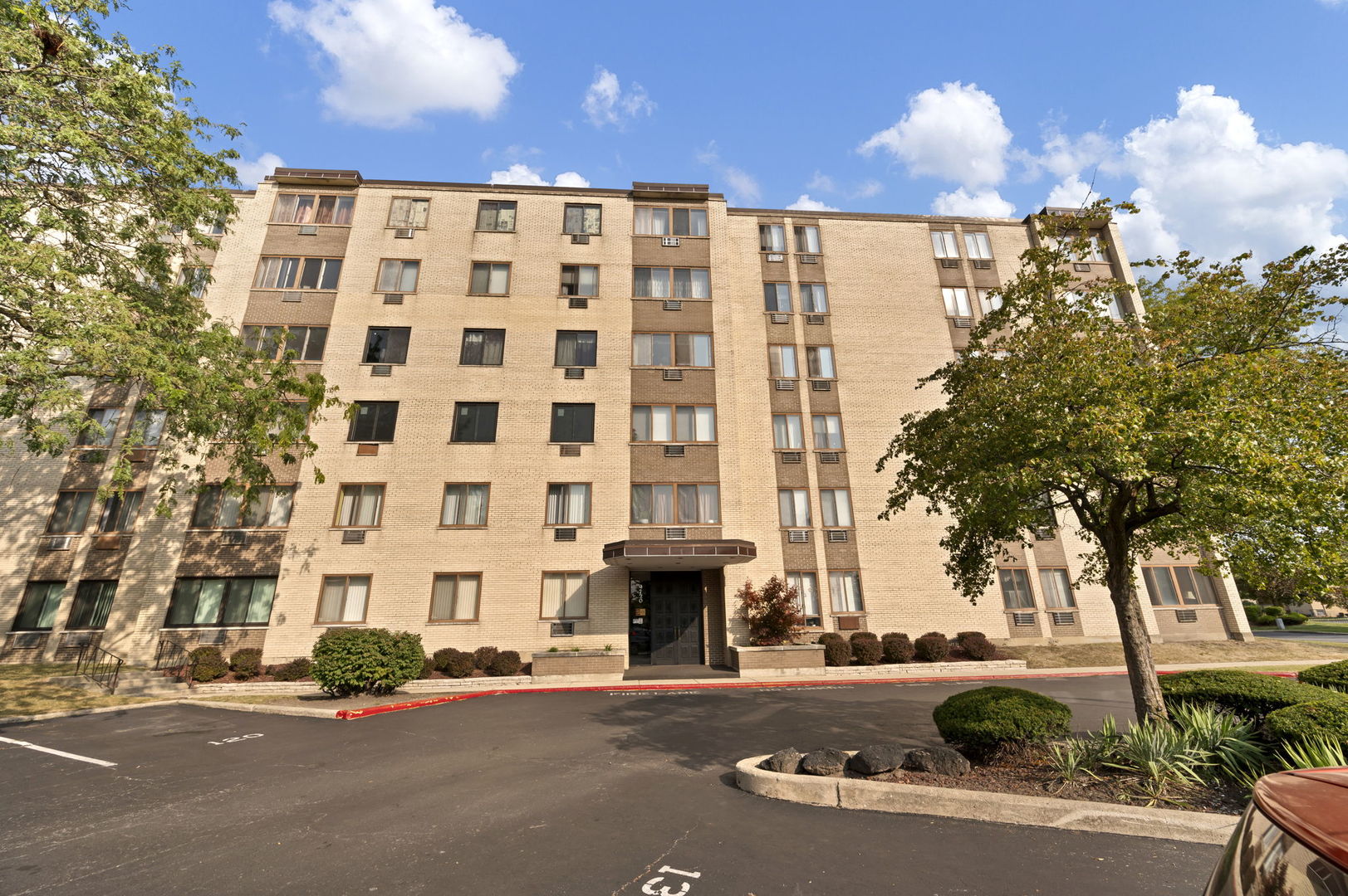 a front view of a building with street view and trees