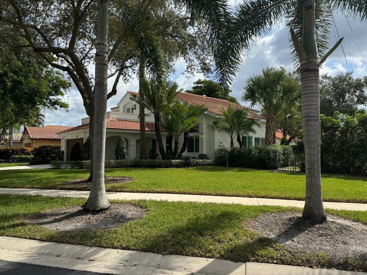 a view of a white house with a big yard and large trees