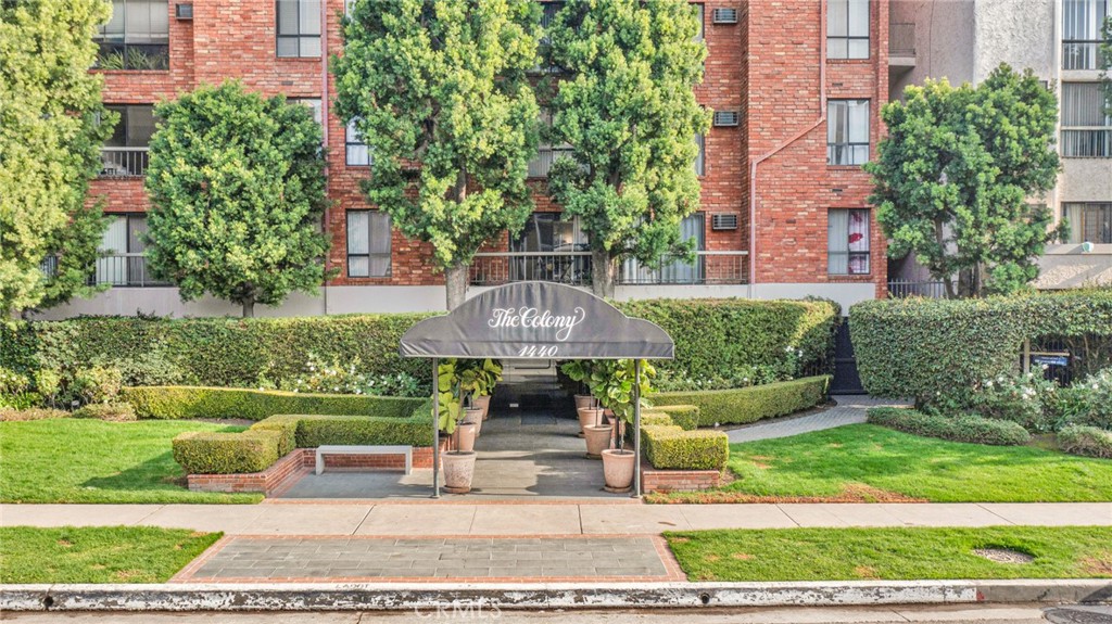 a front view of a building with garden and trees