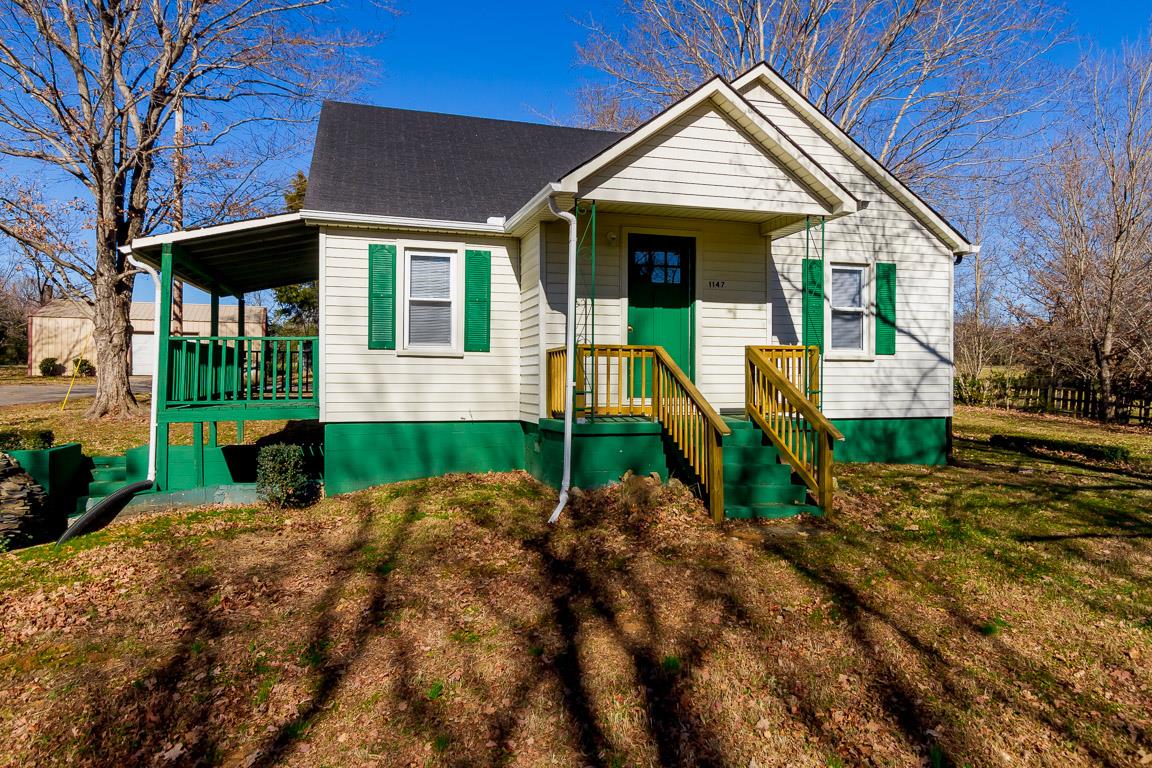 a front view of a house with a yard and potted plants