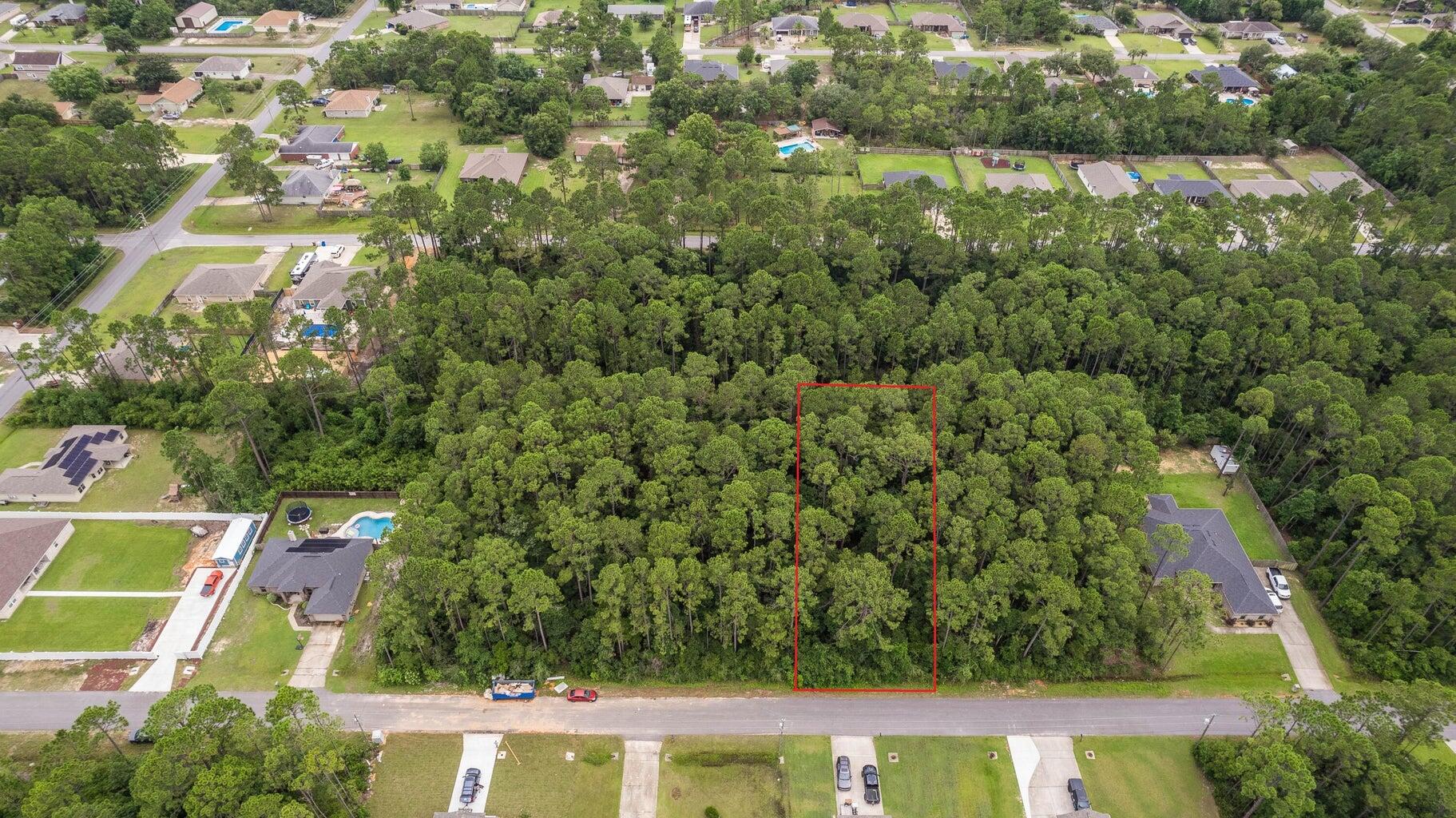 an aerial view of a residential houses with yard and trees in the background