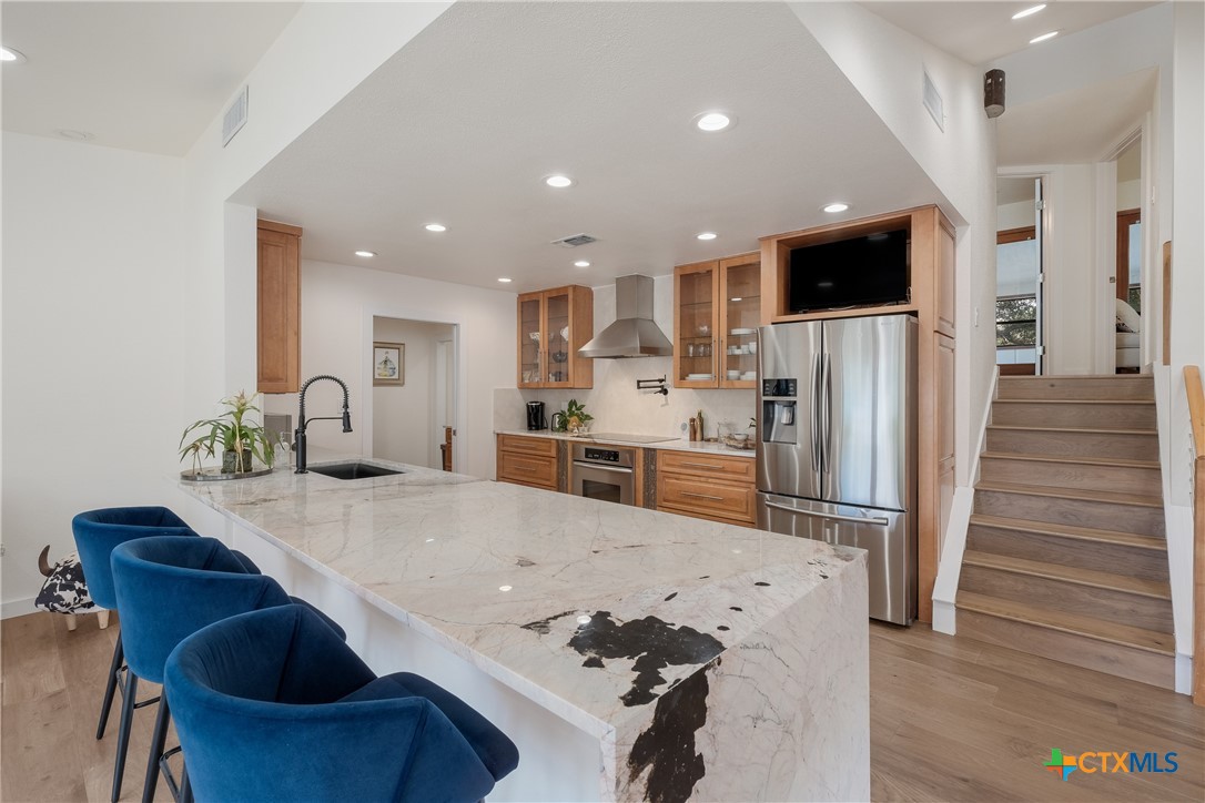 a kitchen with stainless steel appliances kitchen island granite countertop a refrigerator and a stove top oven