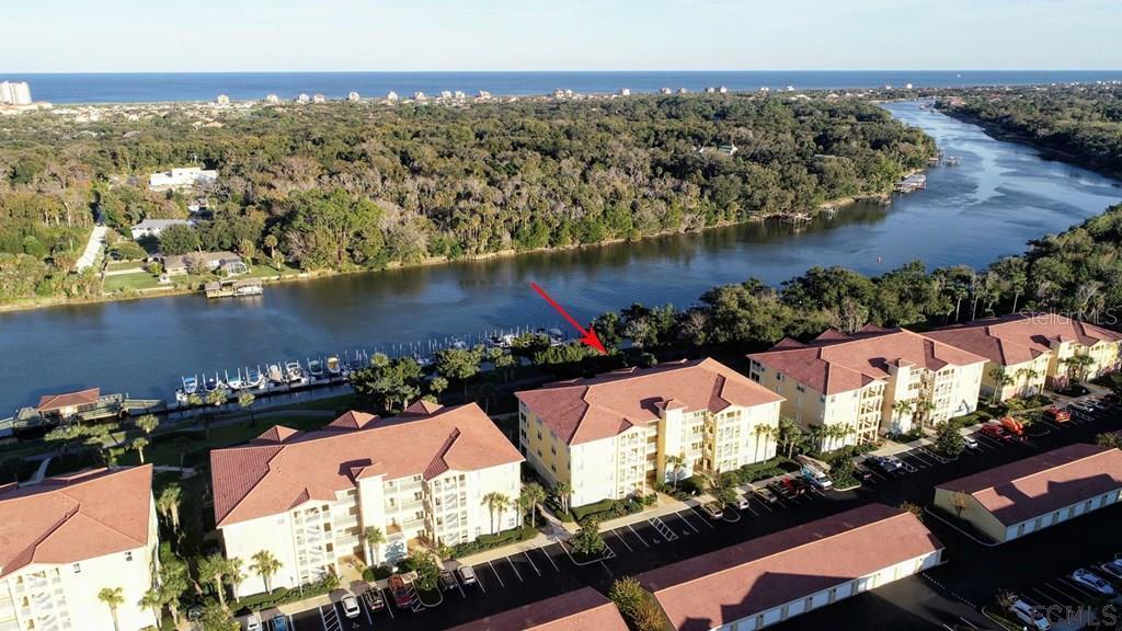 an aerial view of ocean and residential houses with outdoor space