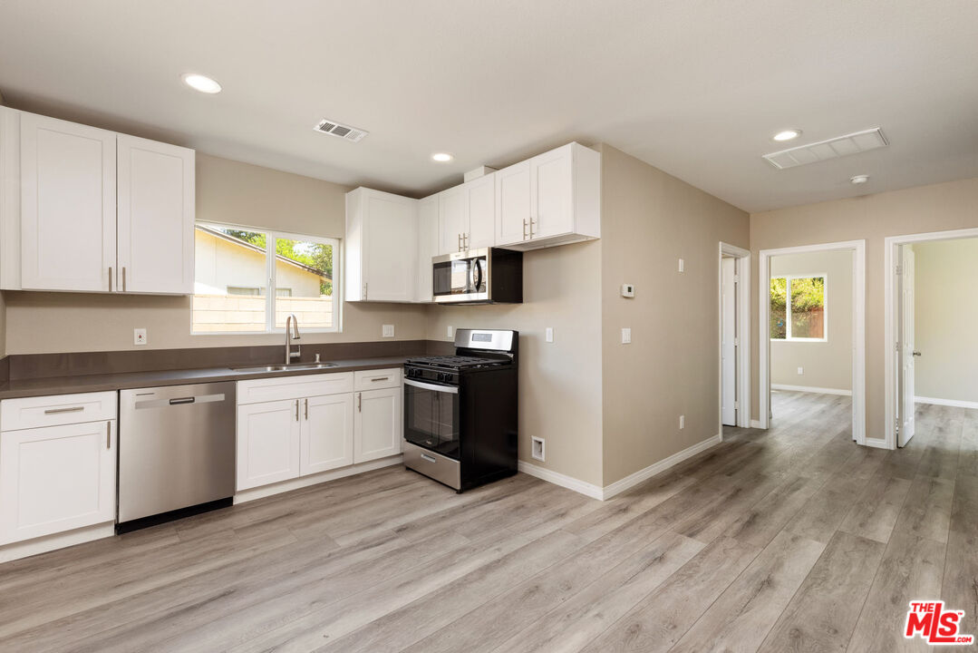 a kitchen with granite countertop a refrigerator and a stove top oven