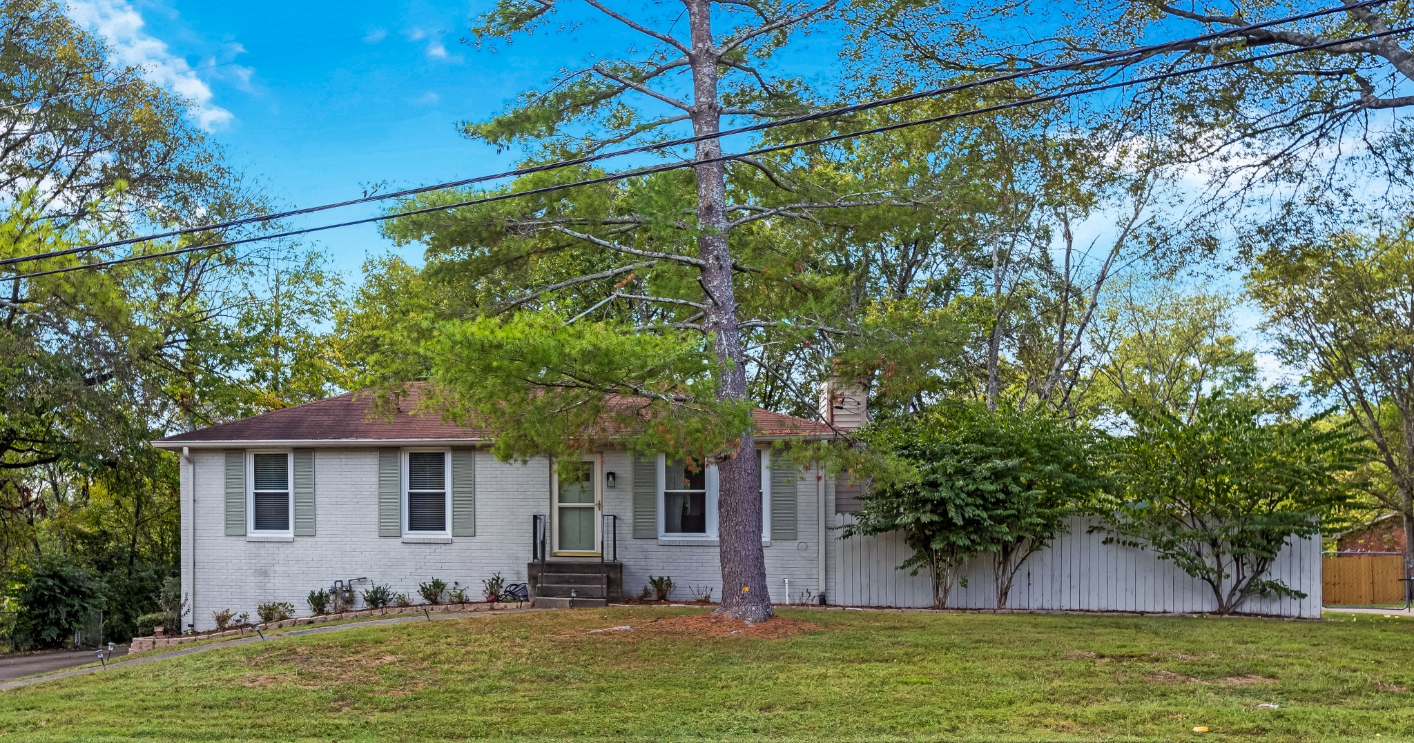 a front view of a house with a garden and tree