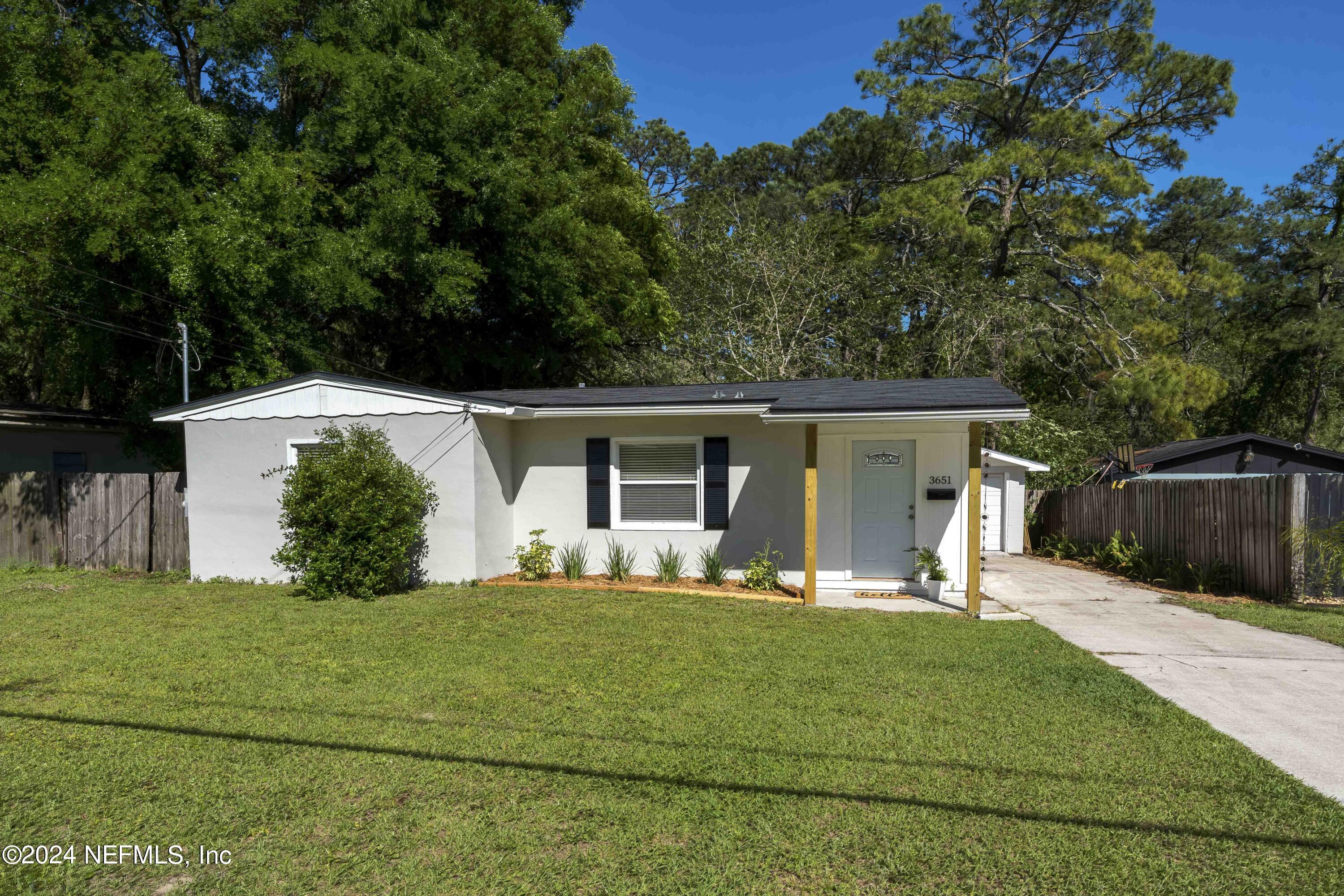 a front view of house with yard and trees in the background