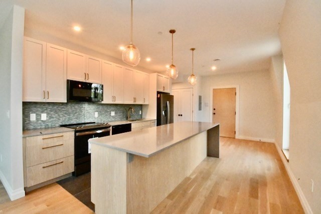 a large kitchen with stainless steel appliances kitchen island granite countertop a stove a sink and white cabinets