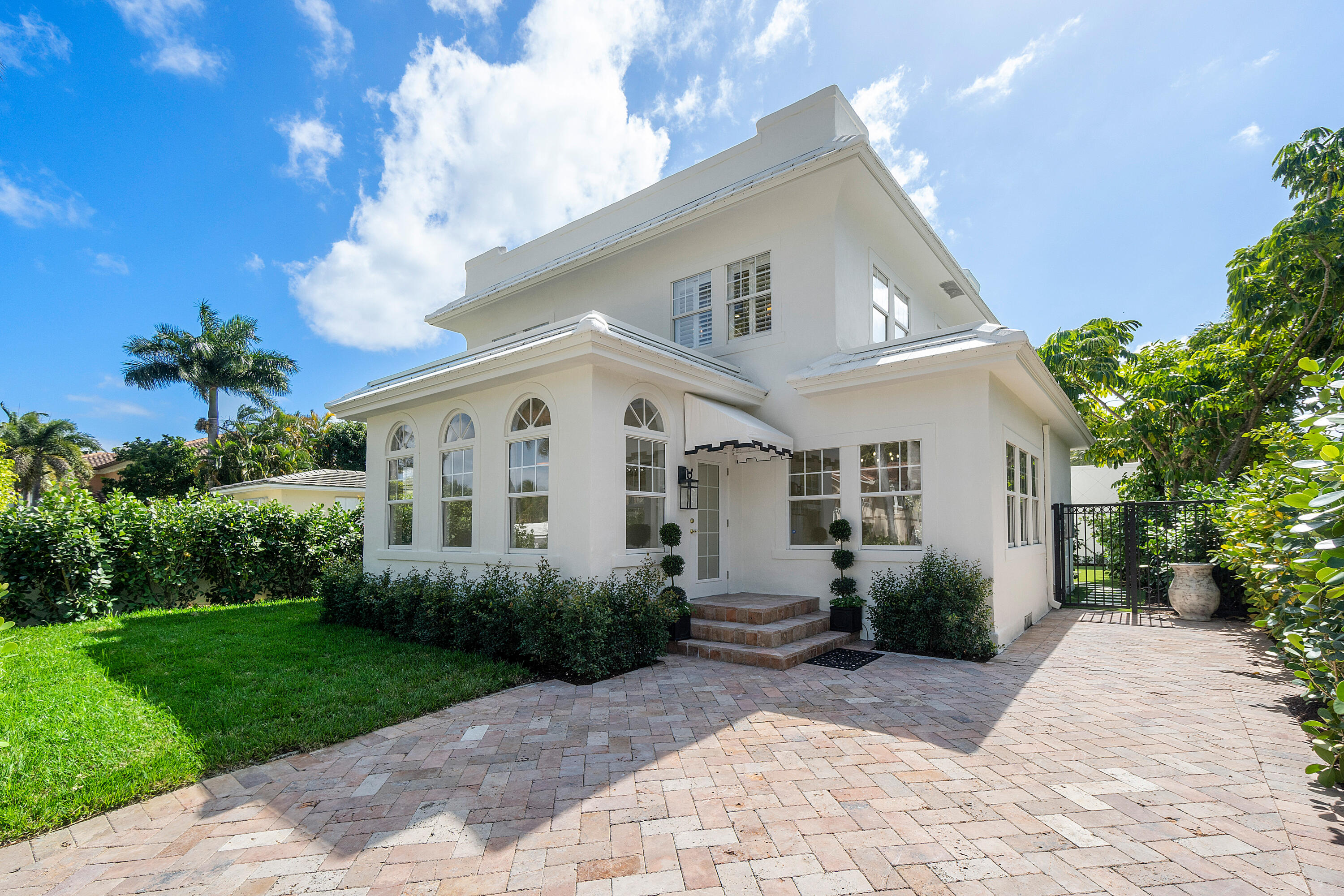 a view of a white house with a yard and potted plants