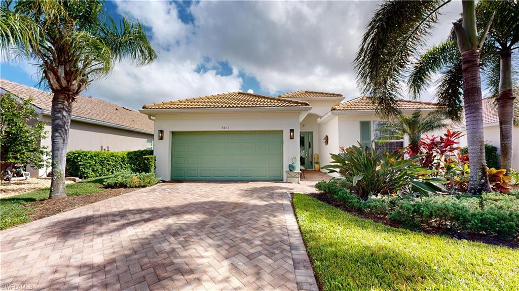 a front view of a house with a garden and palm trees