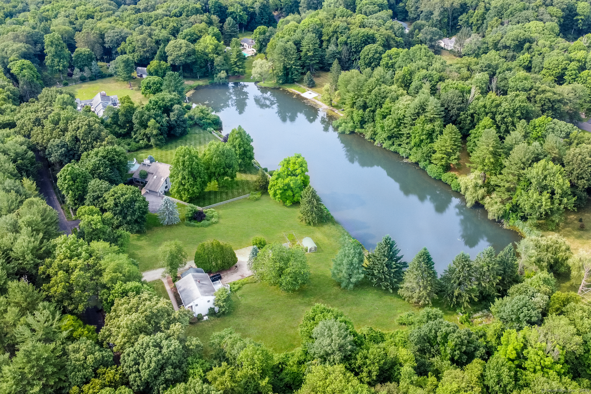 an aerial view of residential house with outdoor space and trees all around