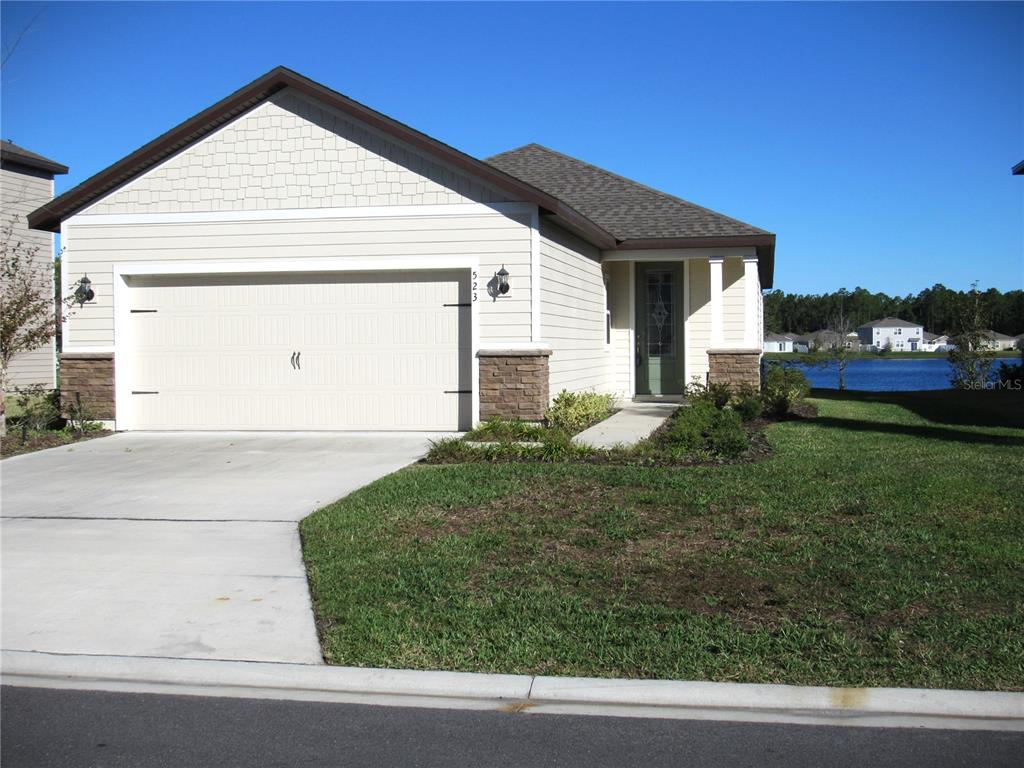 a view of a white house next to a yard and road