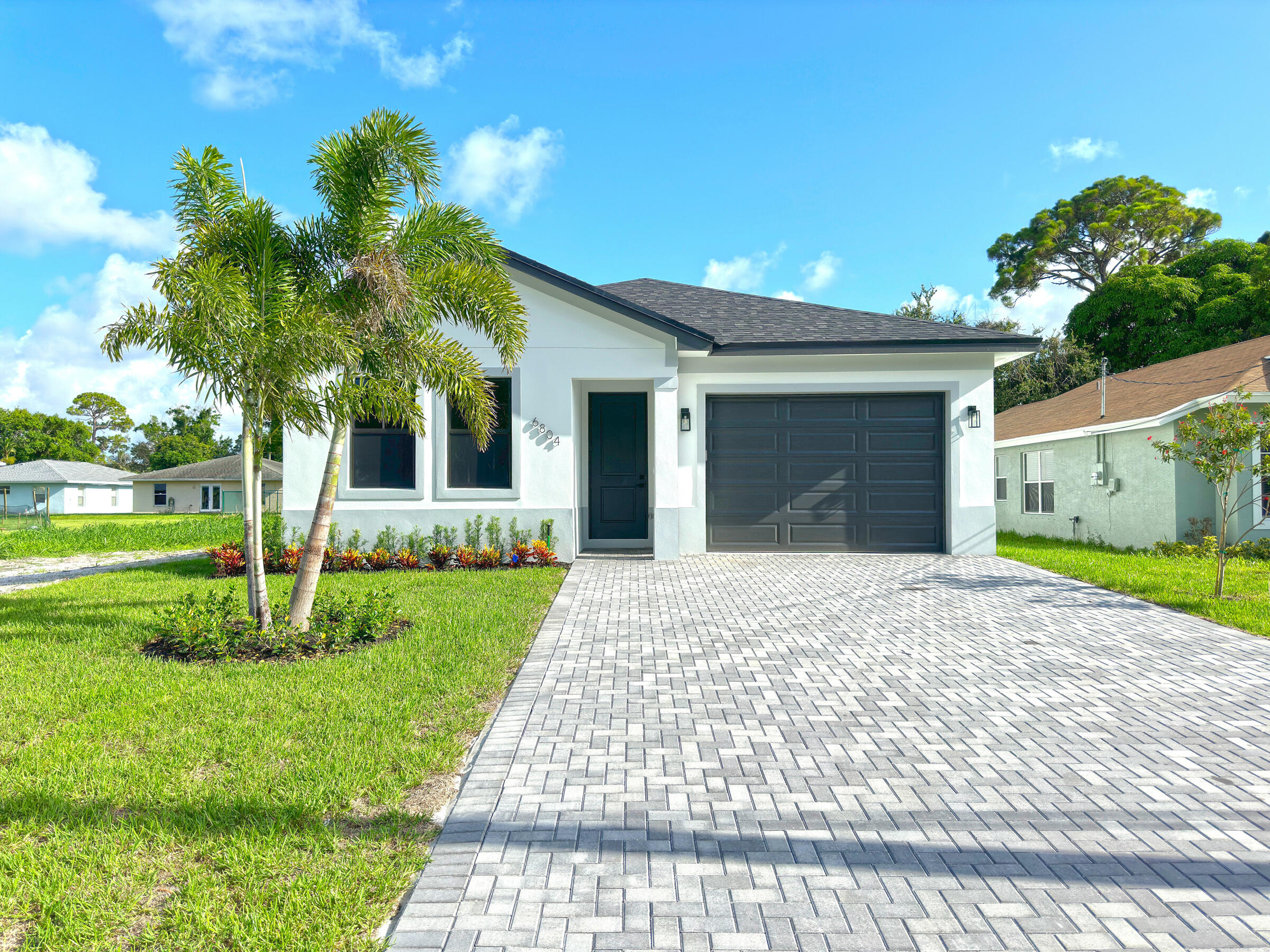 a front view of a house with a yard and potted plants